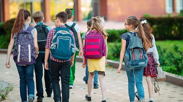 Schulkinder laufen eine Straße entlang.
