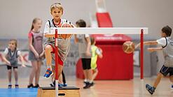 Ein Grundschulkind beim Schulsport mit einem Basketball.