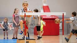 Ein Grundschulkind beim Schulsport mit einem Basketball.
