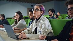 Eine Studentin sitzt mit einem Laptop in einem Vorlesungssaal.
