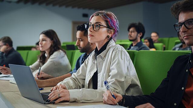 Eine Studentin sitzt mit einem Laptop in einem Vorlesungssaal.