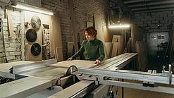 Eine junge Frau steht an einem Tisch mit Kreissäge und sägt ein Brett.