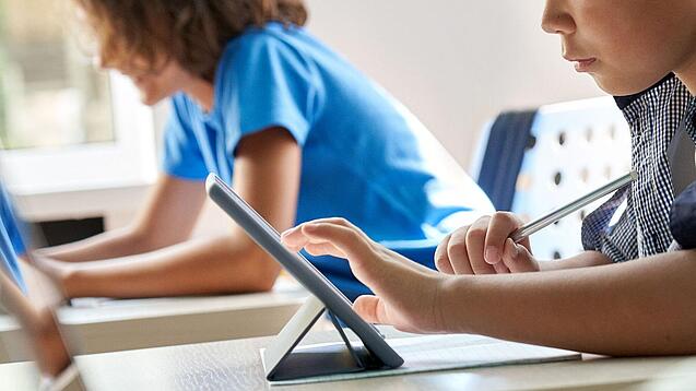Schulkinder arbeiten mit einem Tablet.