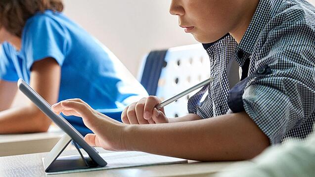 Schulkinder arbeiten mit einem Tablet.