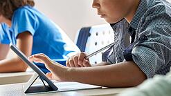 Schulkinder arbeiten mit einem Tablet.