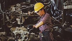 Eine Frau arbeitet in einer Auto-Werkstatt an einem Motor. 