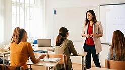 Eine junge Lehrerin in einem Klassenzimmer mit Schüler:innen.