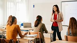 Eine junge Lehrerin in einem Klassenzimmer mit Schüler:innen.