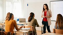 Eine junge Lehrerin in einem Klassenzimmer mit Schüler:innen.