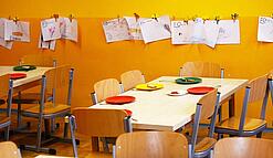Tische in einer Schule sind gedeckt mit Tellern und Besteck.