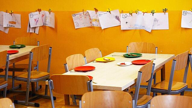 Tische in einer Schule sind gedeckt mit Tellern und Besteck.