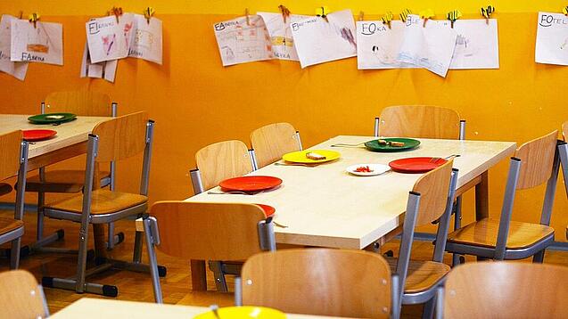 Tische in einer Schule sind gedeckt mit Tellern und Besteck.