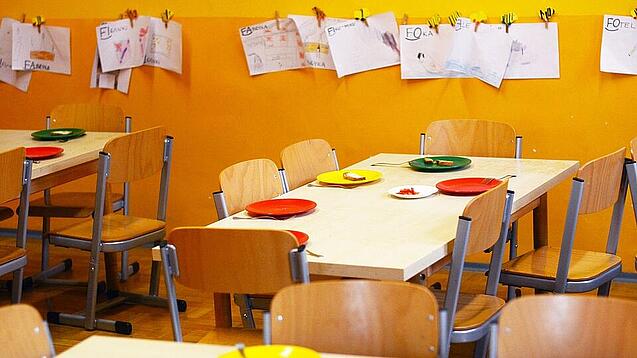 Tische in einer Schule sind gedeckt mit Tellern und Besteck.