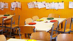 Tische in einer Schule sind gedeckt mit Tellern und Besteck.
