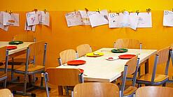 Tische in einer Schule sind gedeckt mit Tellern und Besteck.