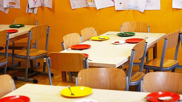 Tische in einer Schule sind gedeckt mit Tellern und Besteck.