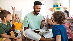 Junger Mann inmitten einer Gruppe Kindergartenkinder.