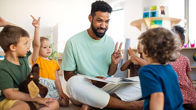 Junger Mann inmitten einer Gruppe Kindergartenkinder.