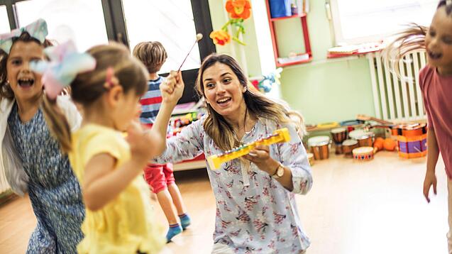 Kinder spielen mit einer Erzieherin in der Kita.