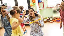 Kinder spielen mit einer Erzieherin in der Kita.