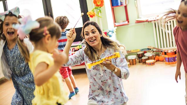 Kinder spielen mit einer Erzieherin in der Kita.