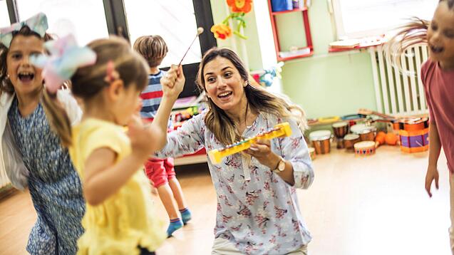 Kinder spielen mit einer Erzieherin in der Kita.
