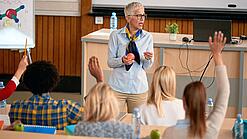 Professorin doziert vor einer Gruppe Studierender in einem Hörsaal.