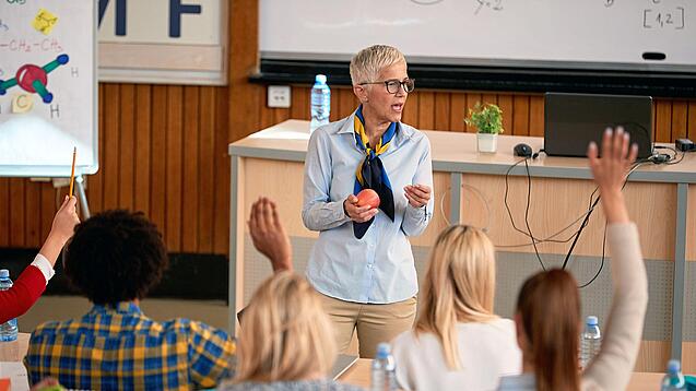 Professorin doziert vor einer Gruppe Studierender in einem Hörsaal.