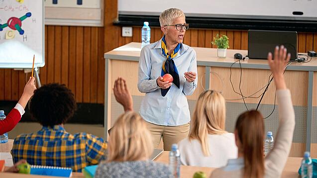 Professorin doziert vor einer Gruppe Studierender in einem Hörsaal.