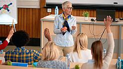 Professorin doziert vor einer Gruppe Studierender in einem Hörsaal.