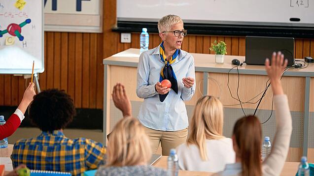 Professorin doziert vor einer Gruppe Studierender in einem Hörsaal.