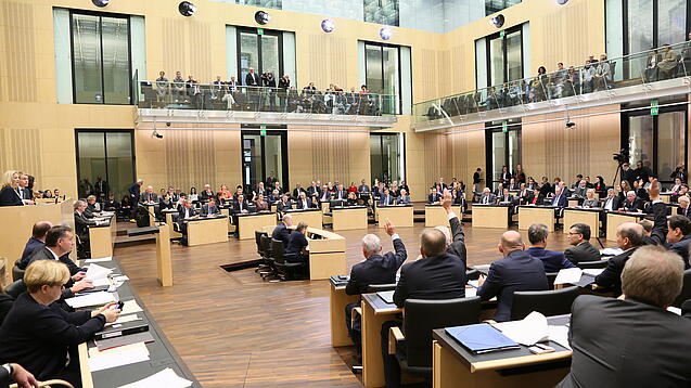 Viele Menschen sitzen an Tischen im Bundesrat.