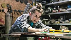 Junge Frau arbeitet in einer Werkstatt.