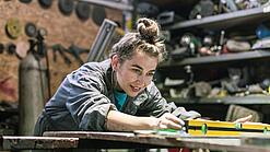 Junge Frau arbeitet in einer Werkstatt.