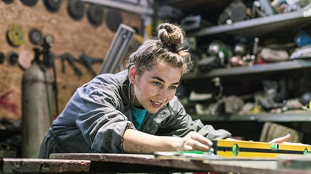 Junge Frau arbeitet in einer Werkstatt.