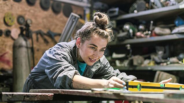 Junge Frau arbeitet in einer Werkstatt.