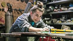 Junge Frau arbeitet in einer Werkstatt.