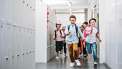 Kinder laufen in einem Schulflur.