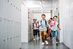 Kinder laufen in einem Schulflur.