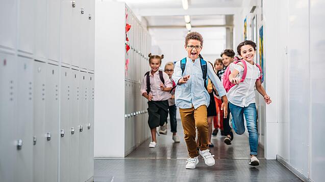 Kinder laufen in einem Schulflur.