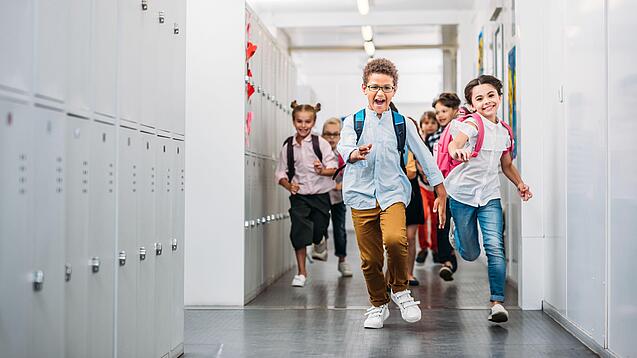 Kinder laufen in einem Schulflur.