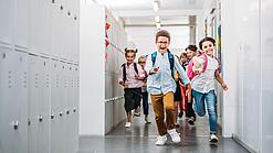 Kinder laufen in einem Schulflur.