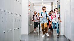Kinder laufen in einem Schulflur.