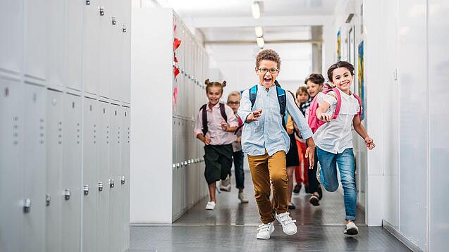 Kinder laufen in einem Schulflur.