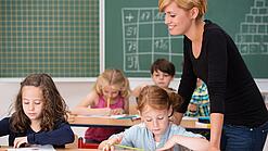 Junge Lehrerin beaufsichtigt Kinder in einer Grundschulklasse.