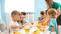 Eine Gruppe von Kindergartenkindern sitzt an einem Tisch und isst. 