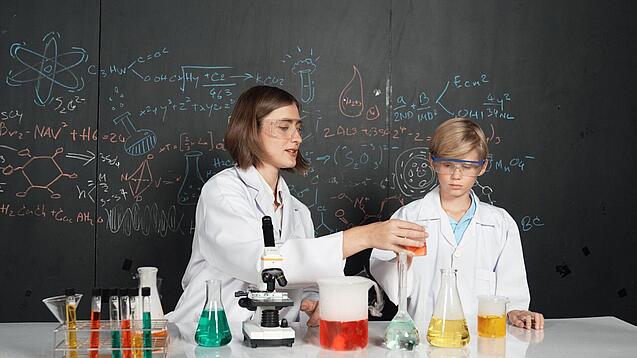 Ein Schüler und eine Lehrerin führen ein Chemie-Experiment durch.