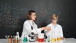 Ein Schüler und eine Lehrerin führen ein Chemie-Experiment durch.