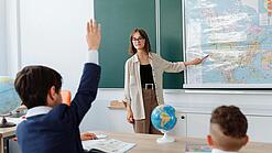 Eine junge Lehrerin steht in einem im Klassenzimmer und unterrichtet.