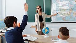 Eine junge Lehrerin steht in einem im Klassenzimmer und unterrichtet.